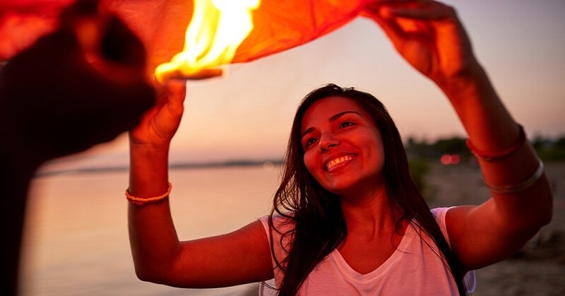 young woman feeling joy as she releases a lantern into the sky