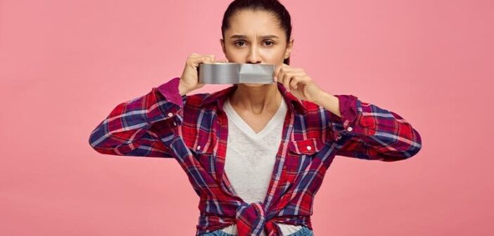 woman putting tape across her mouth to illustrate keeping your mouth shut