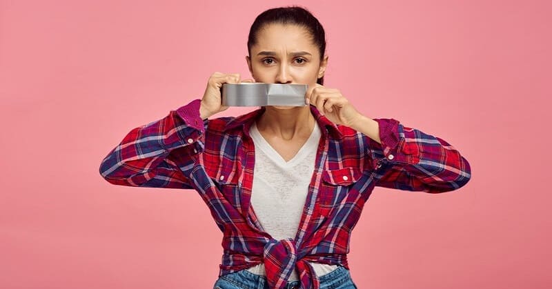 woman putting tape across her mouth to illustrate keeping your mouth shut