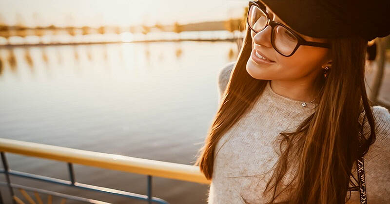 young smiling woman standing by river after changing her life