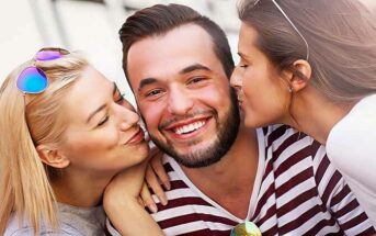 guy being kissed on the cheek by two women - illustrating dating multiple people