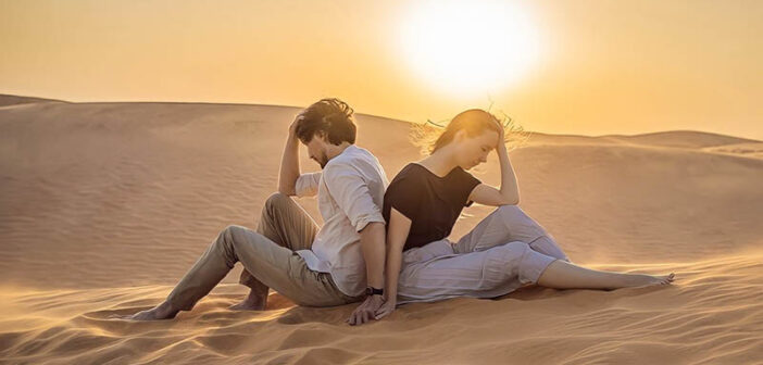 upset couple sitting back to back in desert - illustrating falling for the wrong person