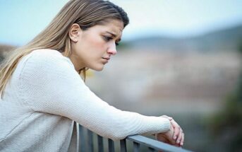 pensive woman standing by railings - illustrating bottling up emotions