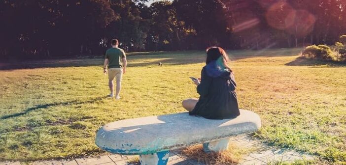 boyfriend being distant as girlfriend sits on bench