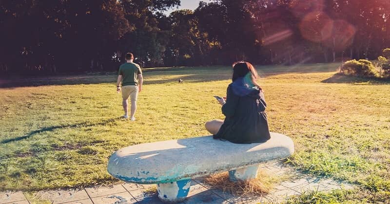 boyfriend being distant as girlfriend sits on bench