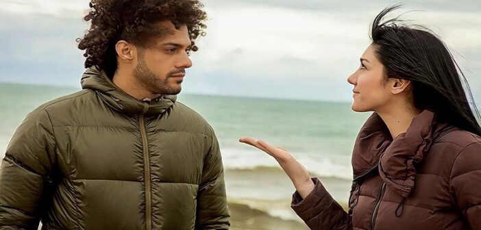 couple standing by the ocean - the girlfriend looks upset because her boyfriend never compliments her