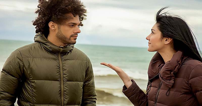 couple standing by the ocean - the girlfriend looks upset because her boyfriend never compliments her