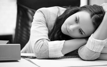 exhausted woman looking hopeless at her work desk - illustrating being tired of life