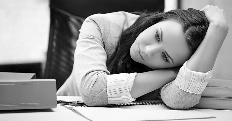 exhausted woman looking hopeless at her work desk - illustrating being tired of life