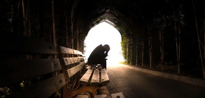 sad person sitting on bench in tunnel - illustrating the fear of losing someone you love