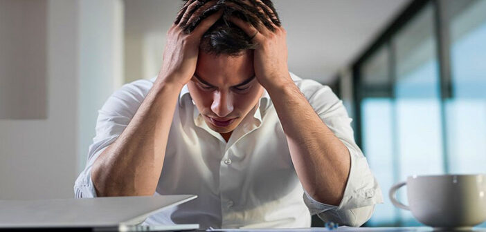 young stressed man at his laptop - illustrating toxic hustle culture