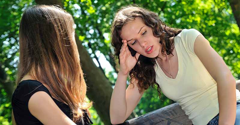 young woman looking disappointed whilst talking to her friend