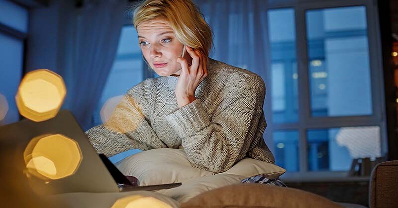 woman on phone and laptop at home - illustrating someone who is always busy