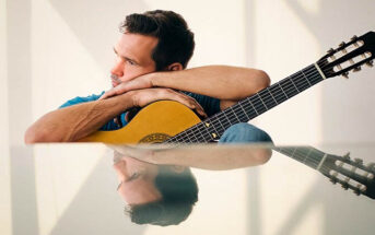 man holding guitar which he has lost interest in playing