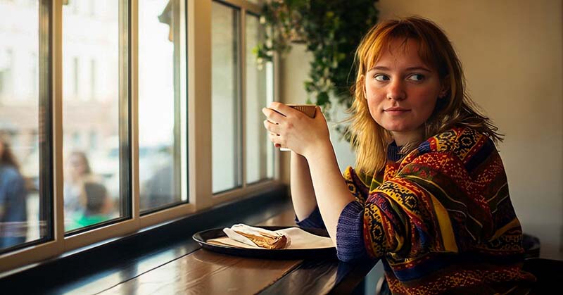 quiet pensive young woman in a cafe - illustrating a sheltered person