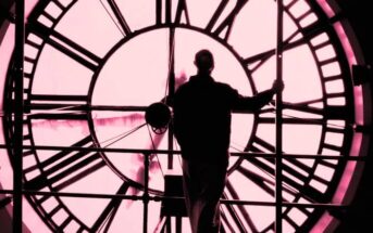 man standing in front of a huge clock face - illustrating the idea of going back in time and changing things
