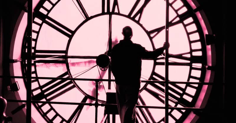 man standing in front of a huge clock face - illustrating the idea of going back in time and changing things