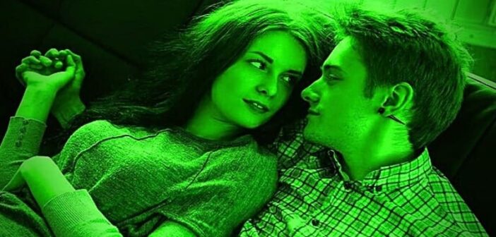 green flags in a relationship - green image of a young couple on a couch looking lovingly into each other's eyes