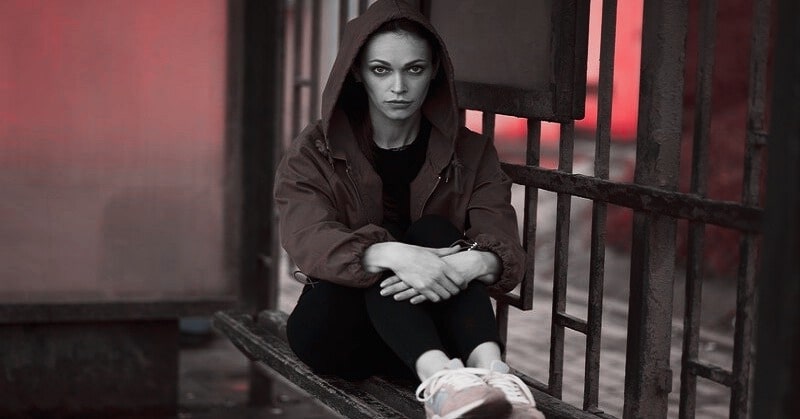 young sad woman sitting at bus stop thinking she is hard to love