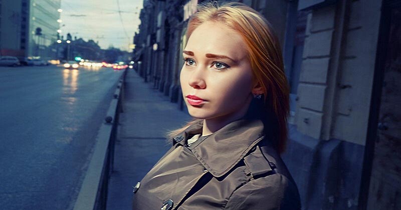 young woman standing on a street looking insecure after being cheated on