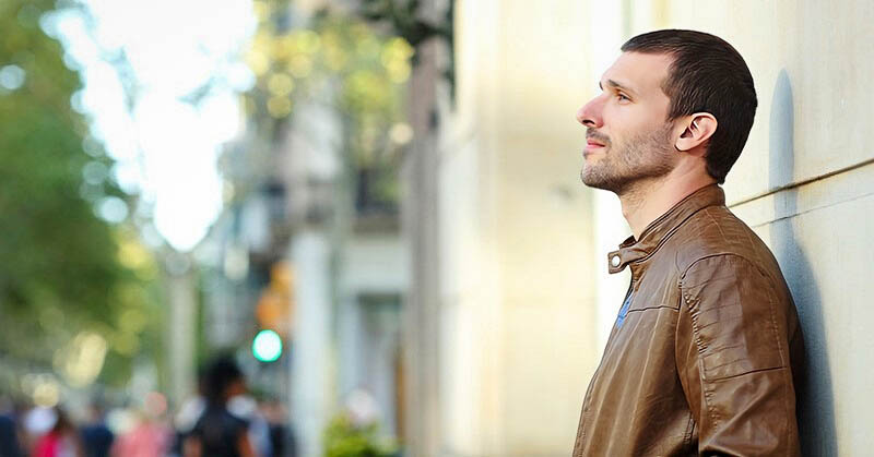 pensive man standing on street who feels life is disappointing