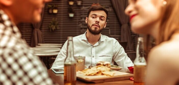 man looking in envy at couple - illustrating a partner and friend who don't like each other