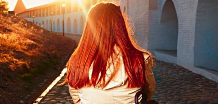 trust the process - red-haired woman walking along a path away from the camera