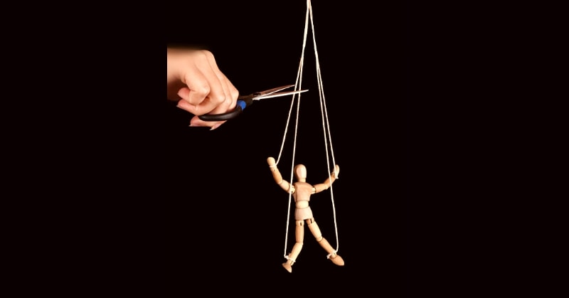 how to cut someone off - photo of hand cutting strings on wooden puppet