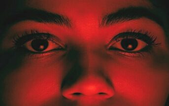 fear of being cheated on - closeup of woman's face illuminated with a red light