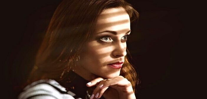 life is complicated - pensive woman with light coming through a blind onto her face