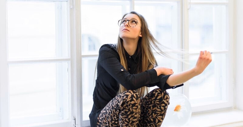 anxiety when things go well - young woman sitting nervously looking up at window