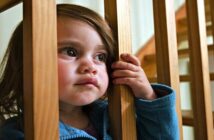 dysfunctional family roles - young girl looking through staircase supports