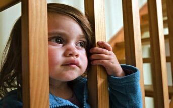 dysfunctional family roles - young girl looking through staircase supports