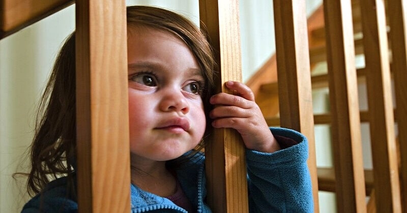 dysfunctional family roles - young girl looking through staircase supports