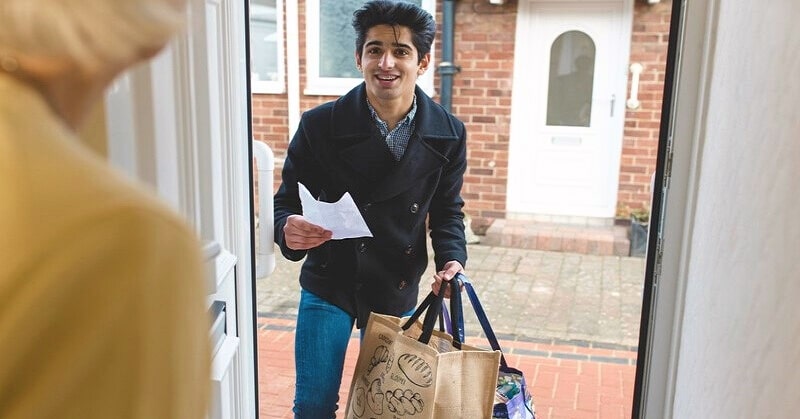 young man doing a kind thing by delivery groceries to elderly neighbor