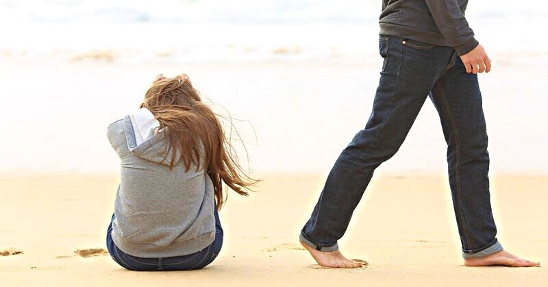 man walking away from his girlfriend on a beach