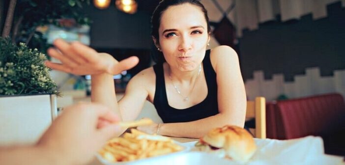 woman batting boyfriend's hand away from her fries