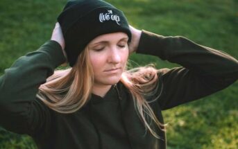 young woman wearing a hat with head in her hands