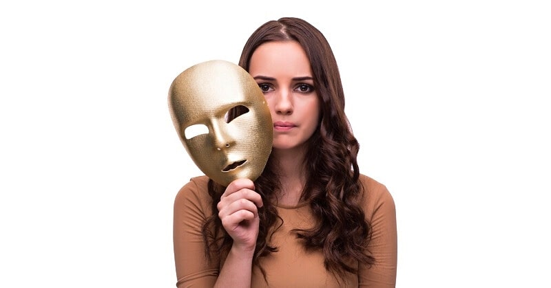 young pensive woman holding mask near her face because she can't be herself around others