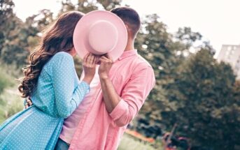 couple kissing behind hat to hide their relationship from the world