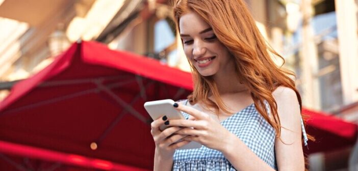 woman looking at her phone smiling at joke sent to her on a dating website