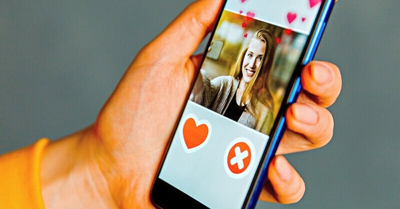 person holding phone with dating app open on the screen