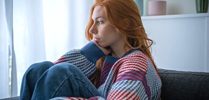 young anxious woman sitting on couch trying to accept her mental health condition