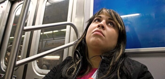 bored woman sitting on a subway train wondering "is this all there is to life?"