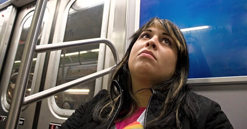 bored woman sitting on a subway train wondering "is this all there is to life?"