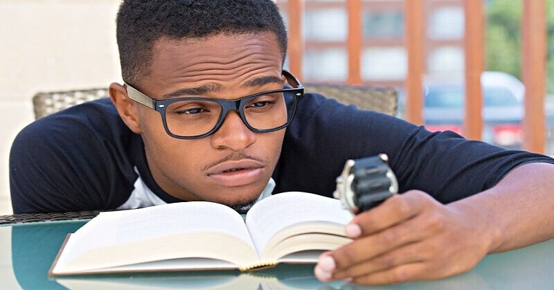 guy struggling with studies as he looks at his watch