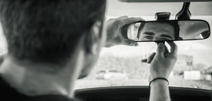 man looking at himself in the rear-view mirror