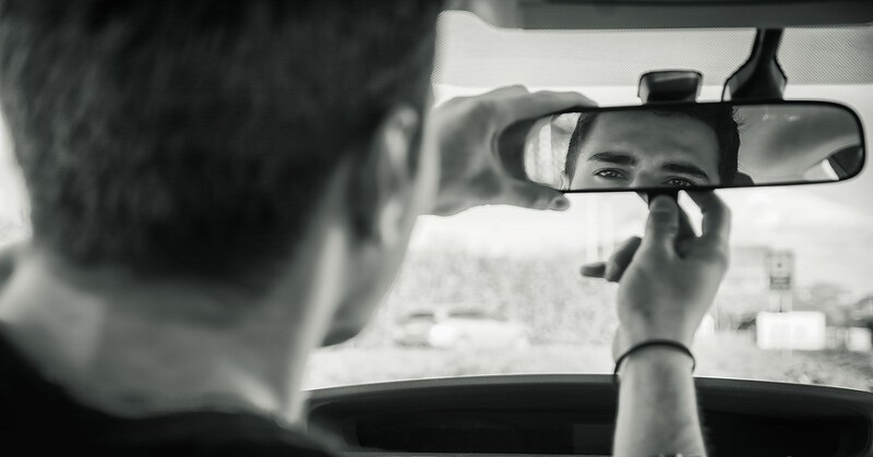 man looking at himself in the rear-view mirror