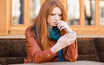 young woman looking anxiously at cell phone