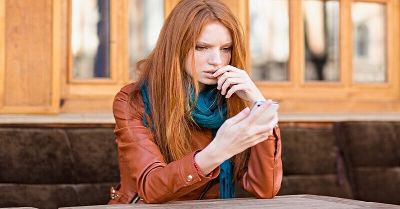 young woman looking anxiously at cell phone